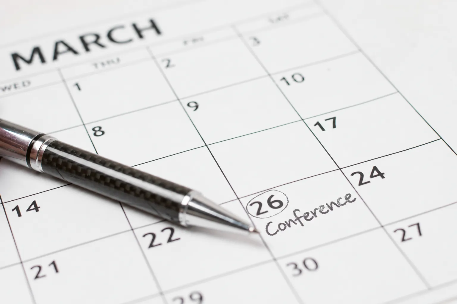 A calendar page for March with the 26th circled and marked Conference, a pen resting beside it